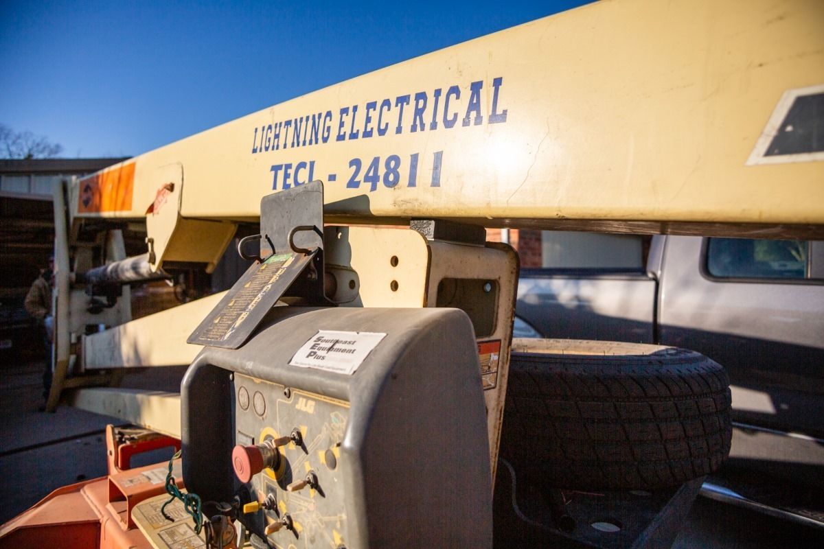 A jlg lift is parked in front of a truck in a parking lot.