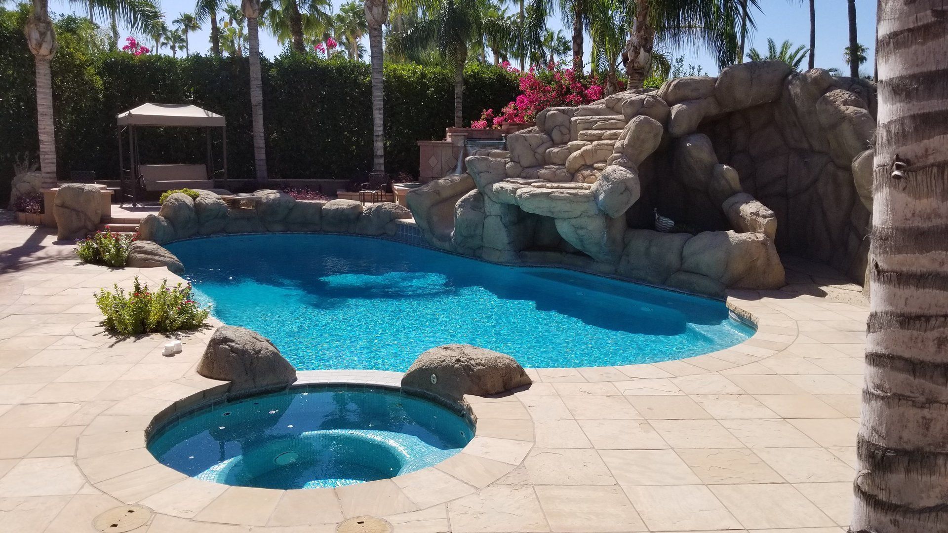 Pool with a rock waterfall, spa, and patio.