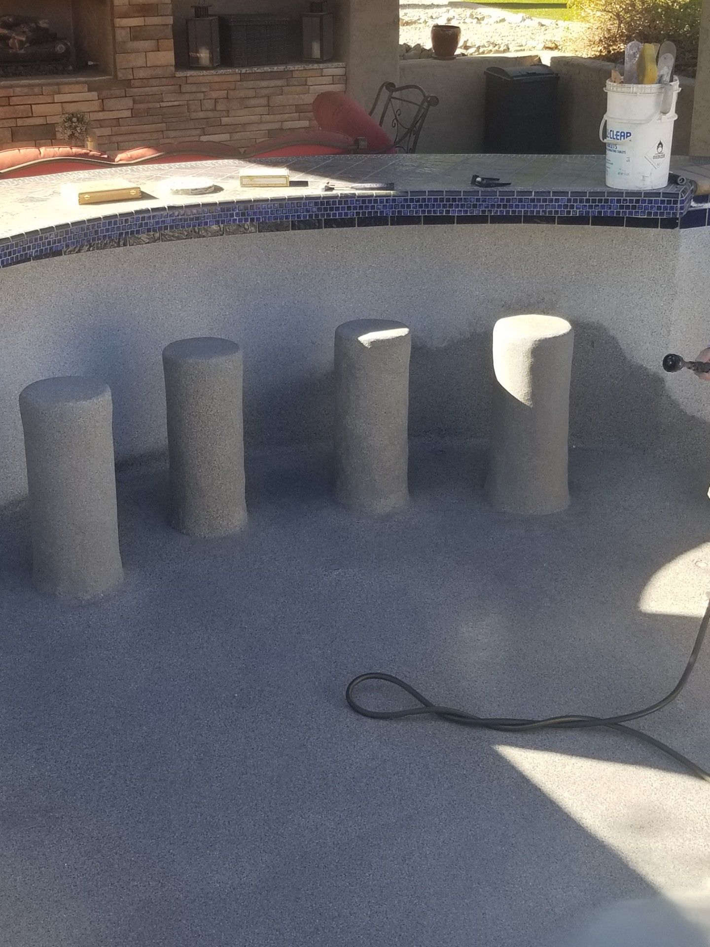 Four gray concrete pillars inside an empty swimming pool, ready for construction.