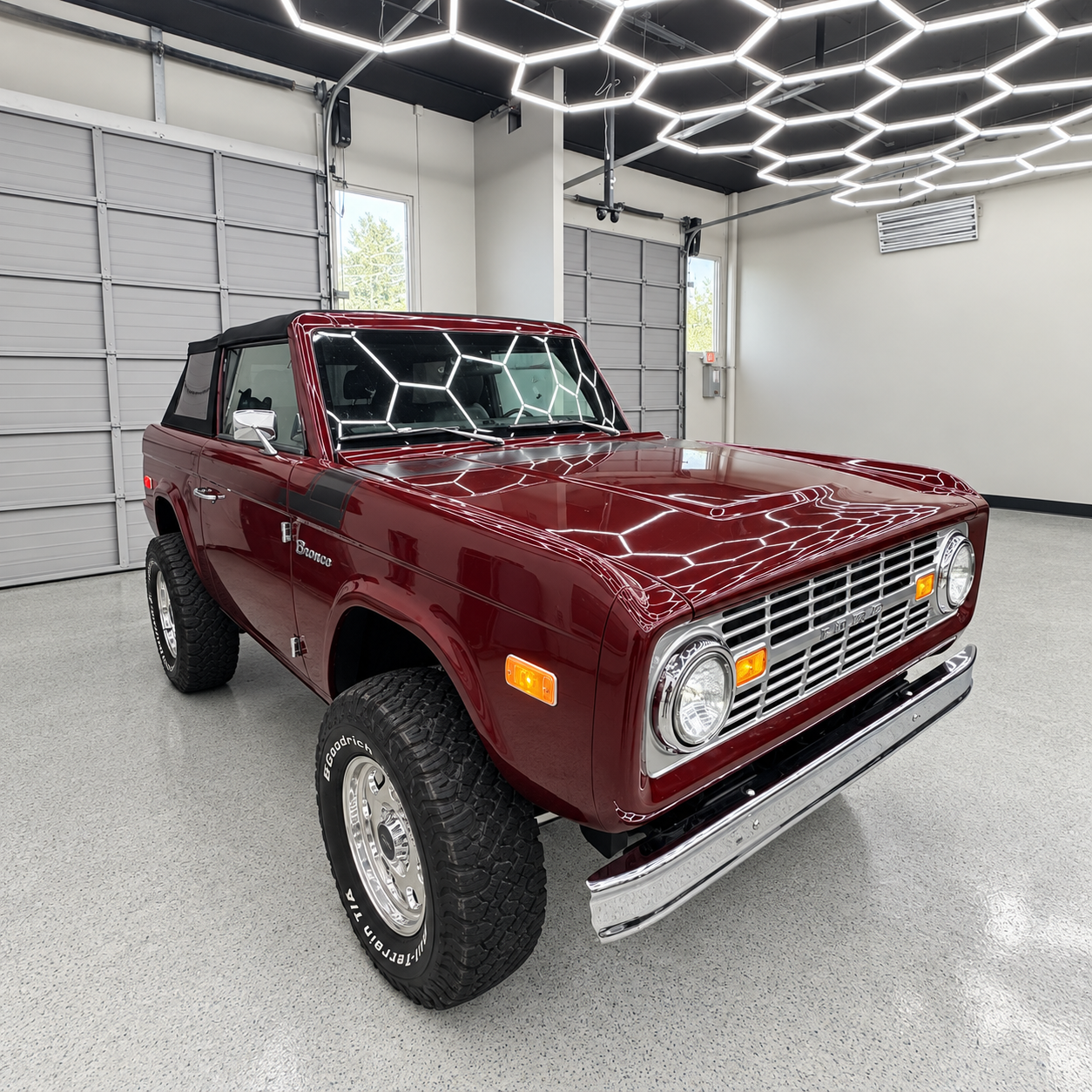 Maroon vintage SUV in a bright garage with white walls and hexagonal ceiling lights