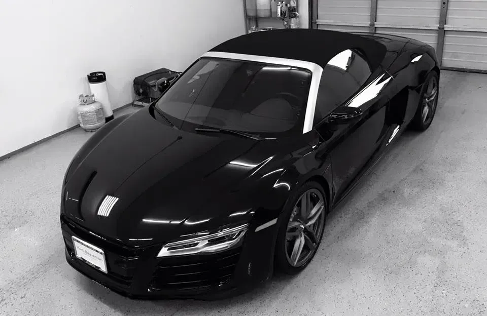 Black Audi R8 convertible parked in a garage.