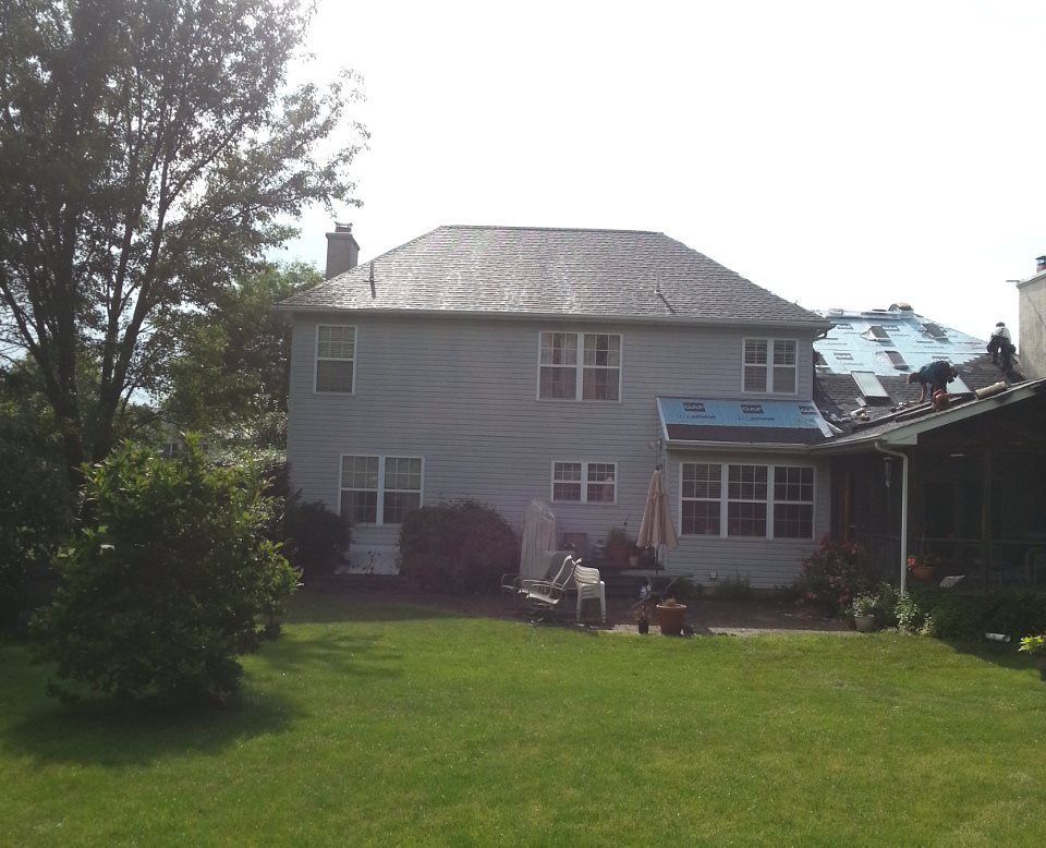 A large white house with a roof that is being installed