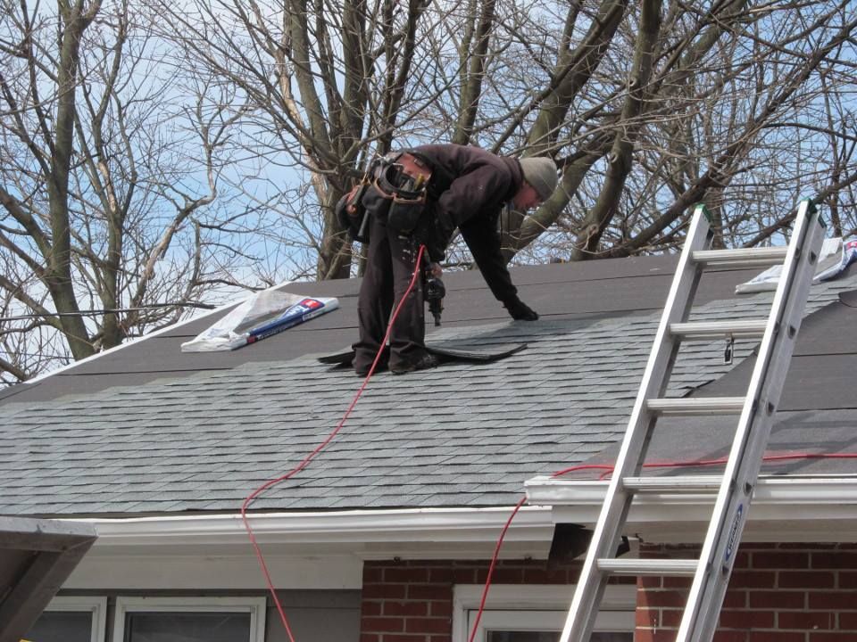 A man is working on a roof next to a ladder.