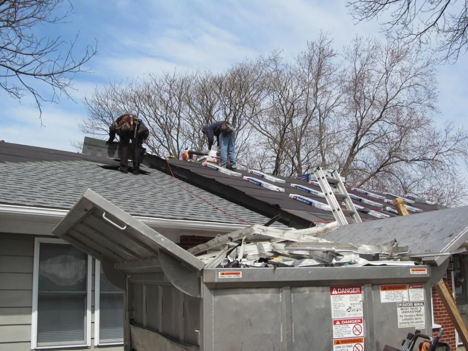 Two men are working on the roof of a house.