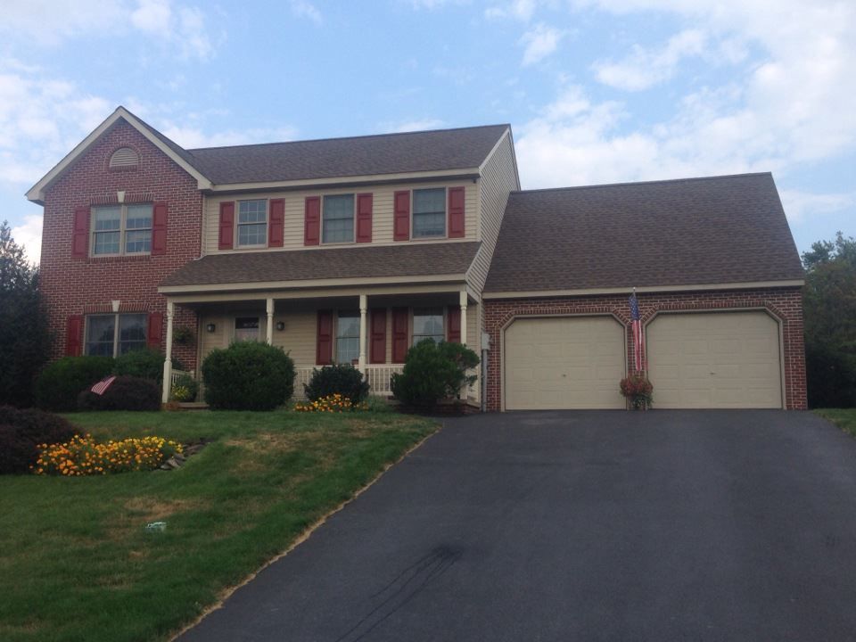 A large brick house with two garage doors and red shutters