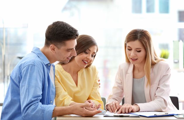 Three coworkers reviewing documents together at a desk in a bright office