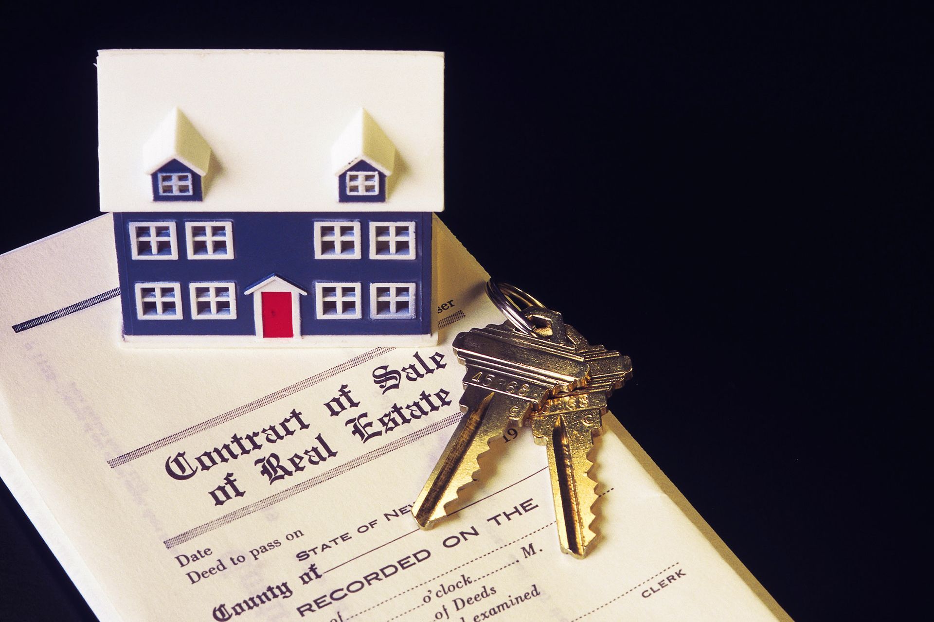 Miniature house model on a real estate contract with a key