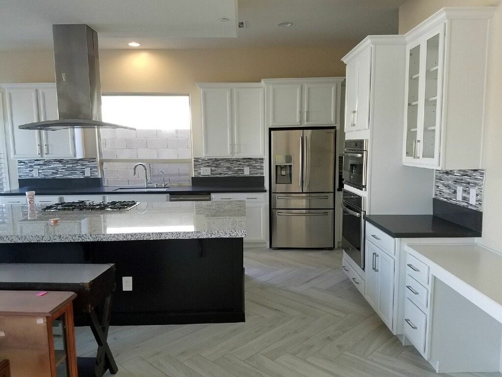 Modern kitchen with white cabinets, stainless steel appliances, and a black island.