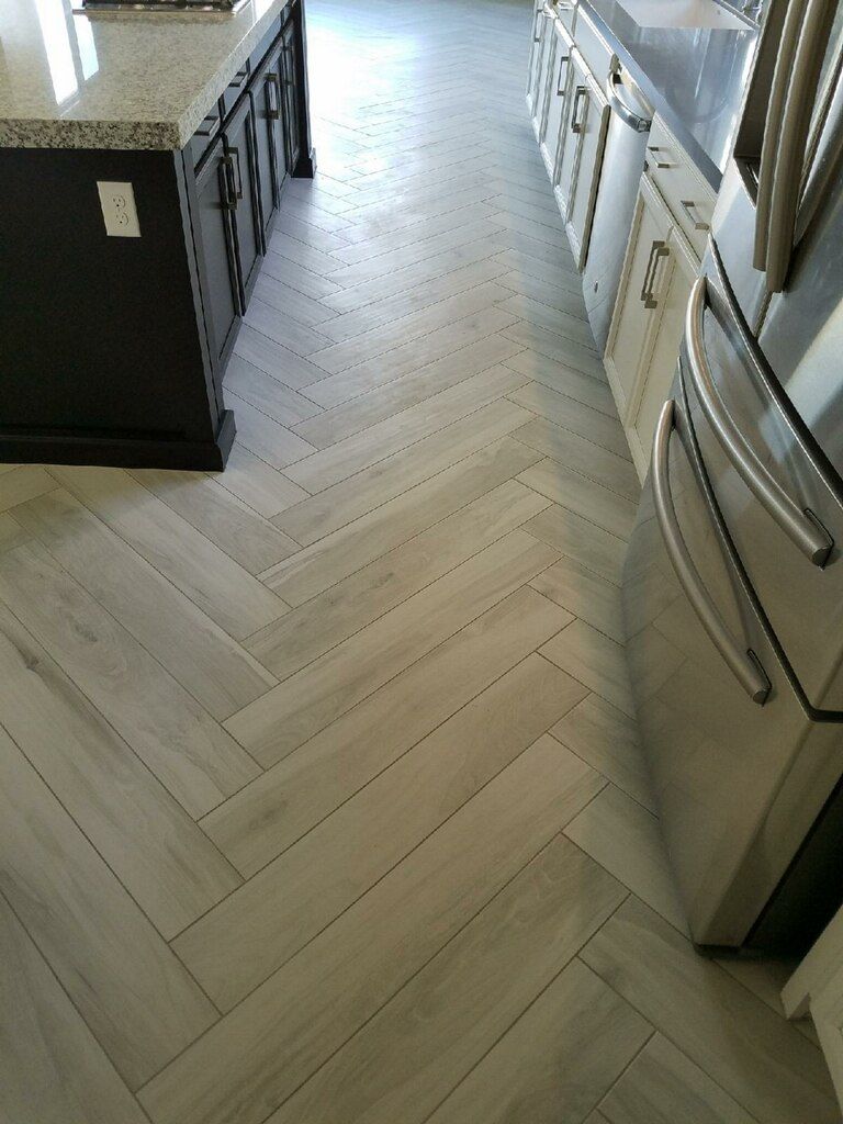 Herringbone pattern tile floor in kitchen, with dark cabinets, stainless steel appliances.