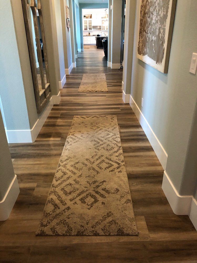 Long hallway with wood-look flooring, two patterned runners, light blue walls, and white trim.