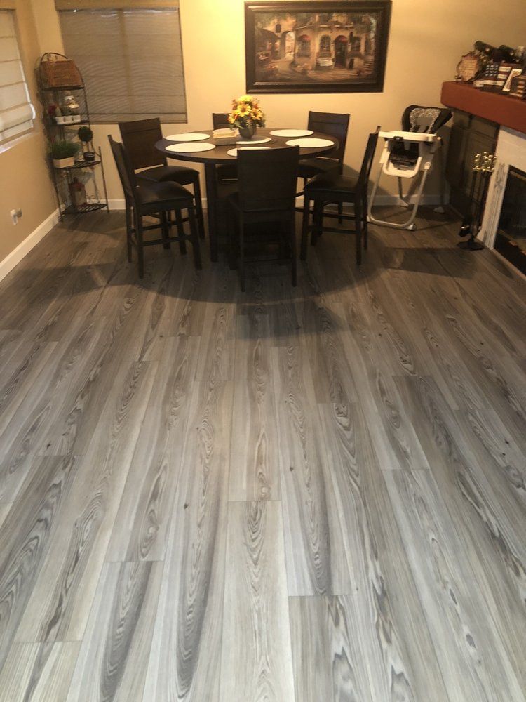 Dining room with gray wood-look flooring, dark table and chairs, and a fireplace.