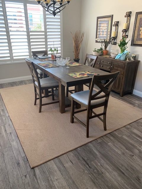 Dining room with a table and chairs on a light beige rug, set against a window and a wooden cabinet.