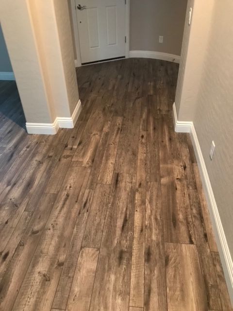 Wooden floor in a hallway, beige walls, white trim, and a white door.