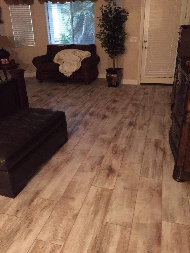Living room with wood-look flooring, brown furniture, a plant, and a window with blinds.