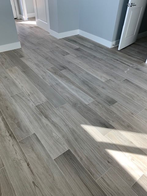 Gray wood-look floor tiles in a room with light blue walls, white trim, and a partially open white door.