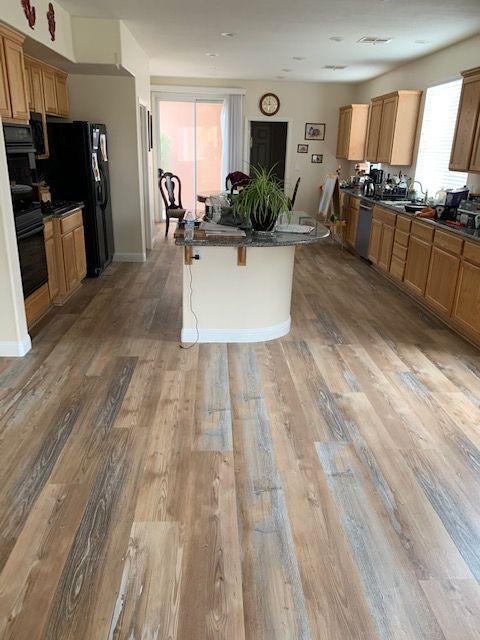 Spacious kitchen with light wood floors, light cabinets, black appliances, and a central island.