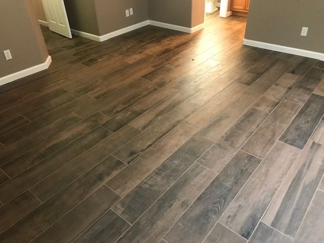 Angled wooden floor planks in a room with neutral walls, white trim, and natural light.