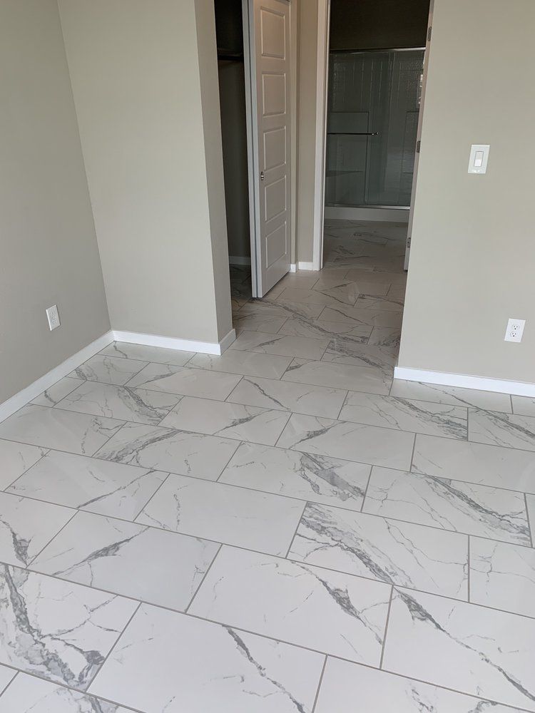 Bedroom with marble-look tiled floor, light gray walls, and a doorway to a bathroom.