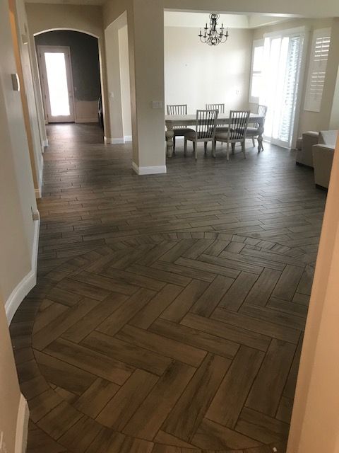 Herringbone pattern wood-look tile floor in a home. Entryway leading to dining and living areas.