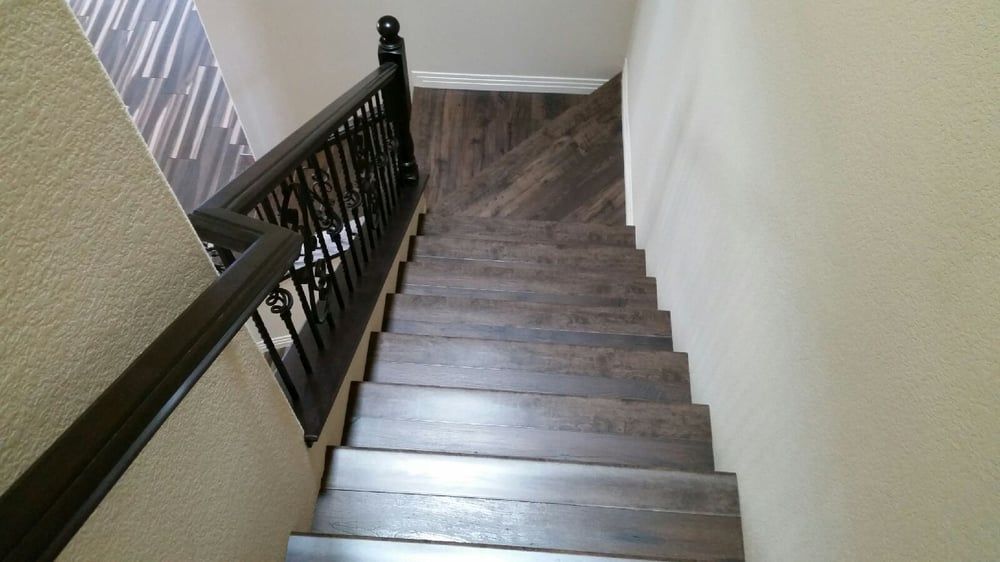 Wooden staircase with a dark brown railing, leading downwards.