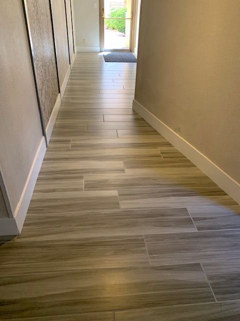 Hallway with wood-look tile flooring and white trim. Open doorway at the end.