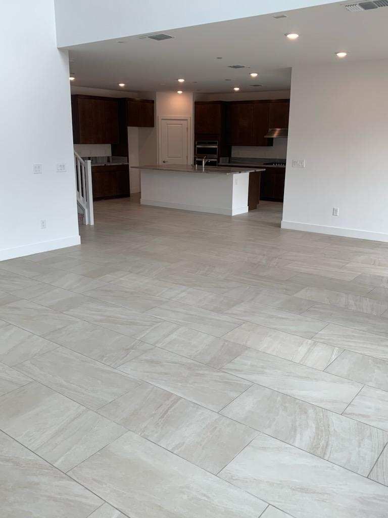 Spacious kitchen with light tile flooring. Dark cabinetry, island, and white walls.