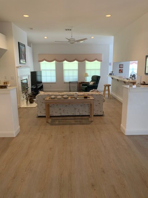 Living room with light wood floors, white walls, and neutral-toned furniture.