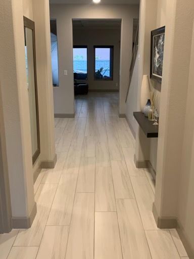 Hallway with light tile floor, beige walls, mirror, and a small shelf with decor.