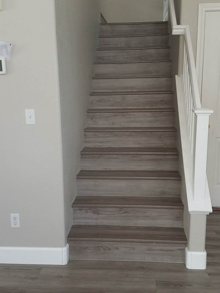 A staircase with wood-look steps and white railing. The wall is beige.