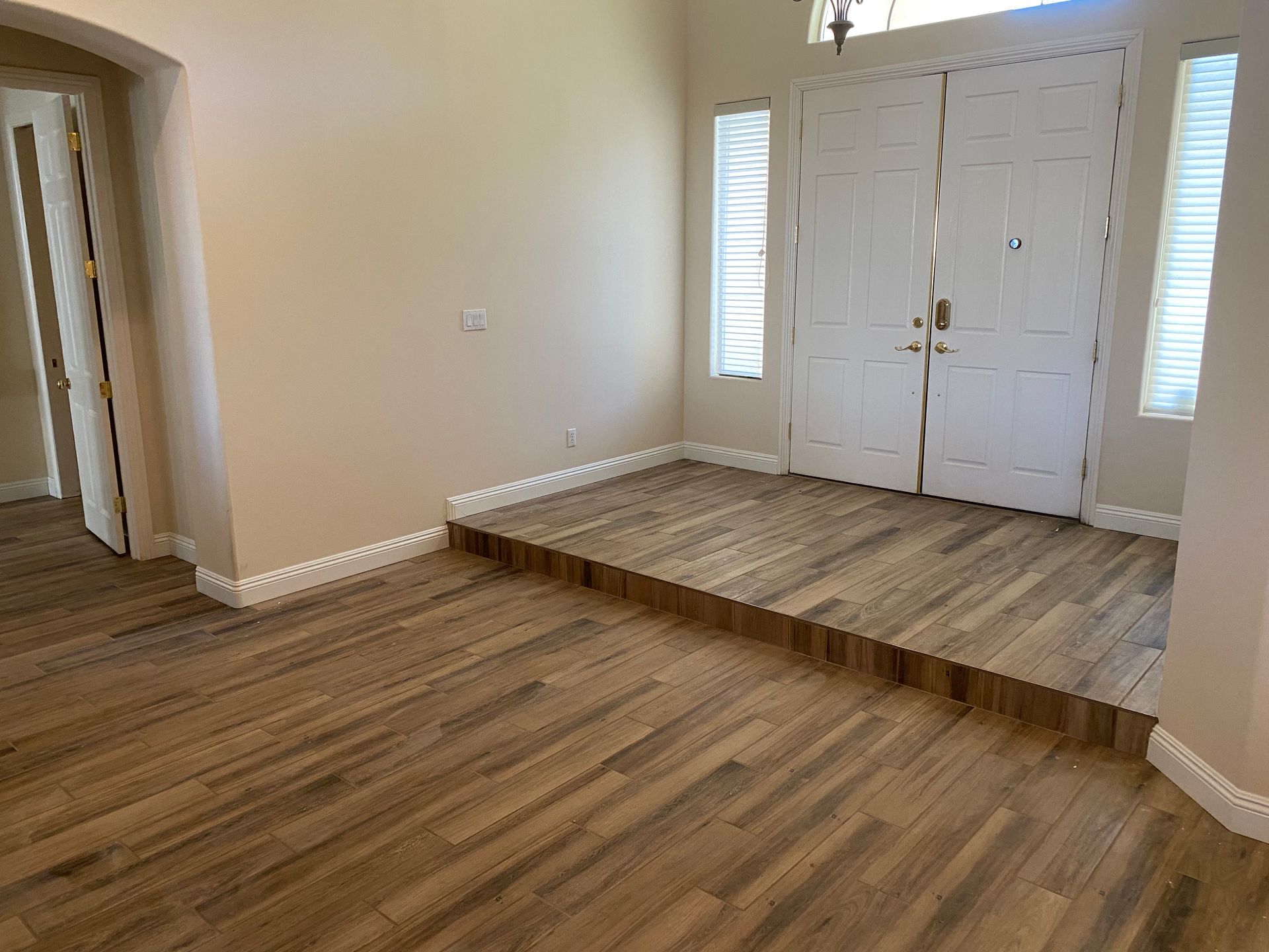 Interior: Entryway with wood-look tile flooring and a raised platform leading to double doors.