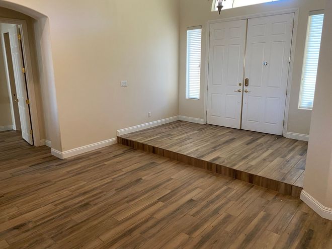 A raised entryway with wood flooring, double doors, and neutral-colored walls.