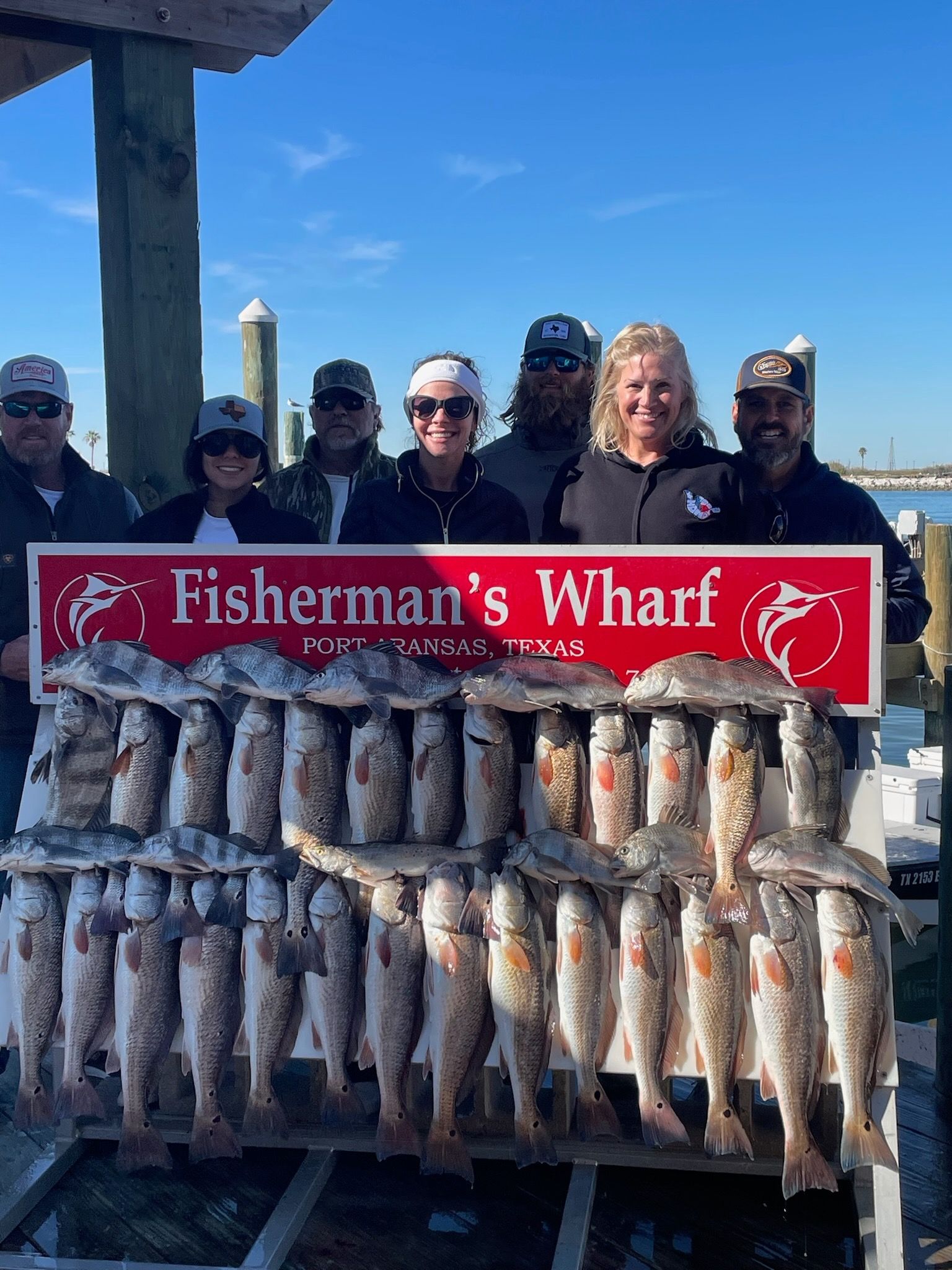 A group of people standing next to a sign that says fisherman 's wharf.