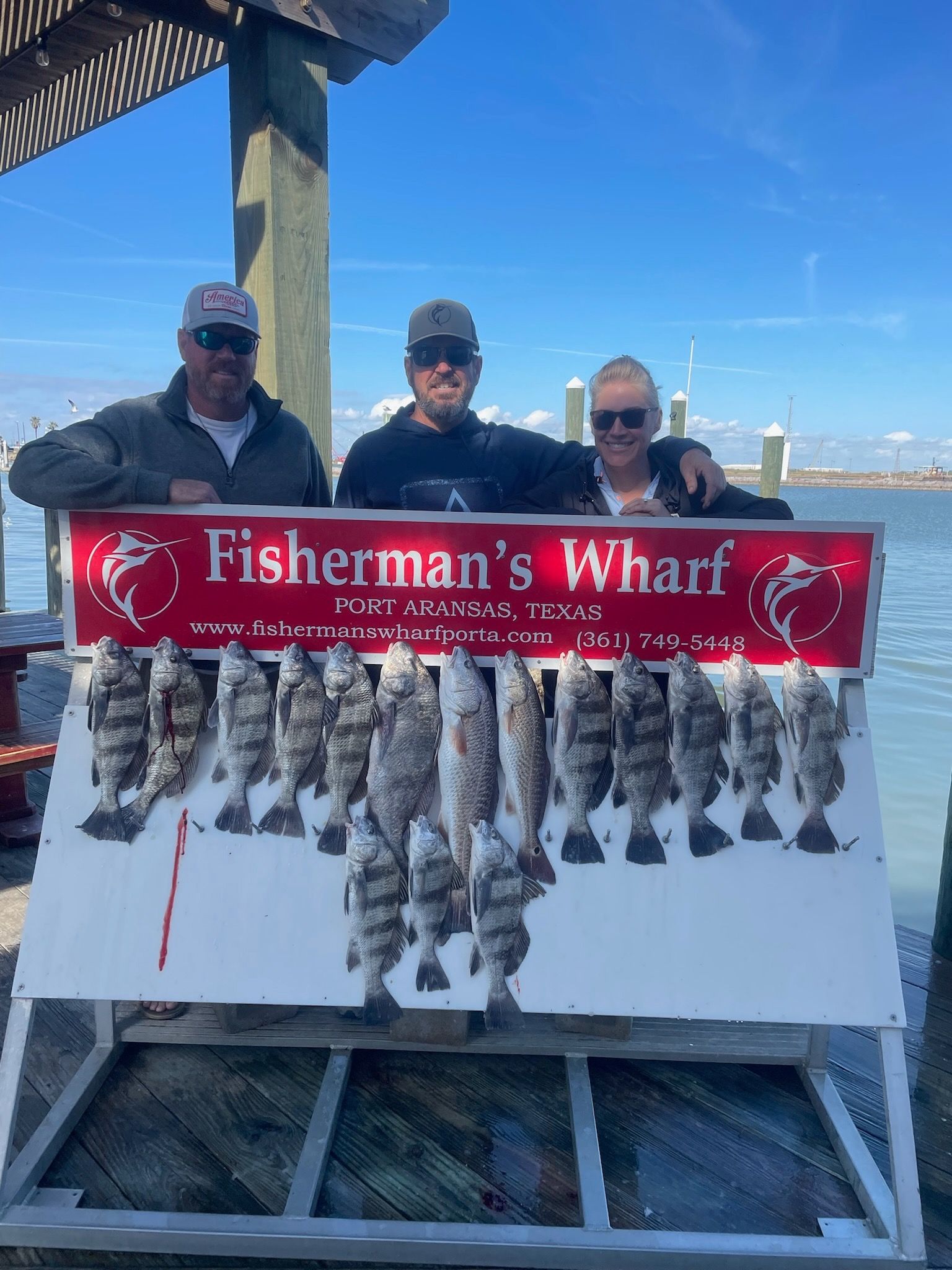 Three men standing next to a sign that says fisherman 's wharf