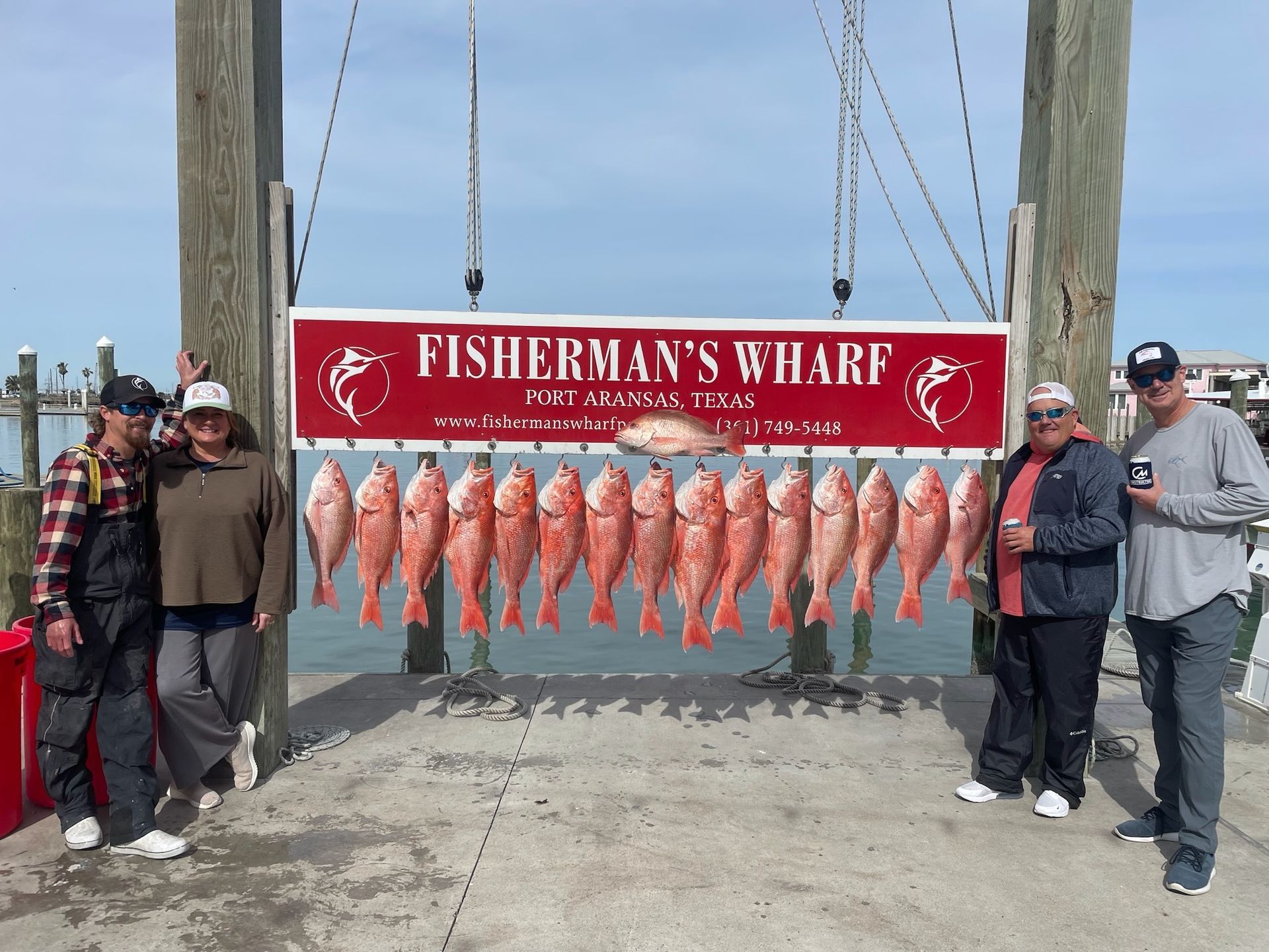 A group of people standing in front of a sign that says fisherman 's wharf