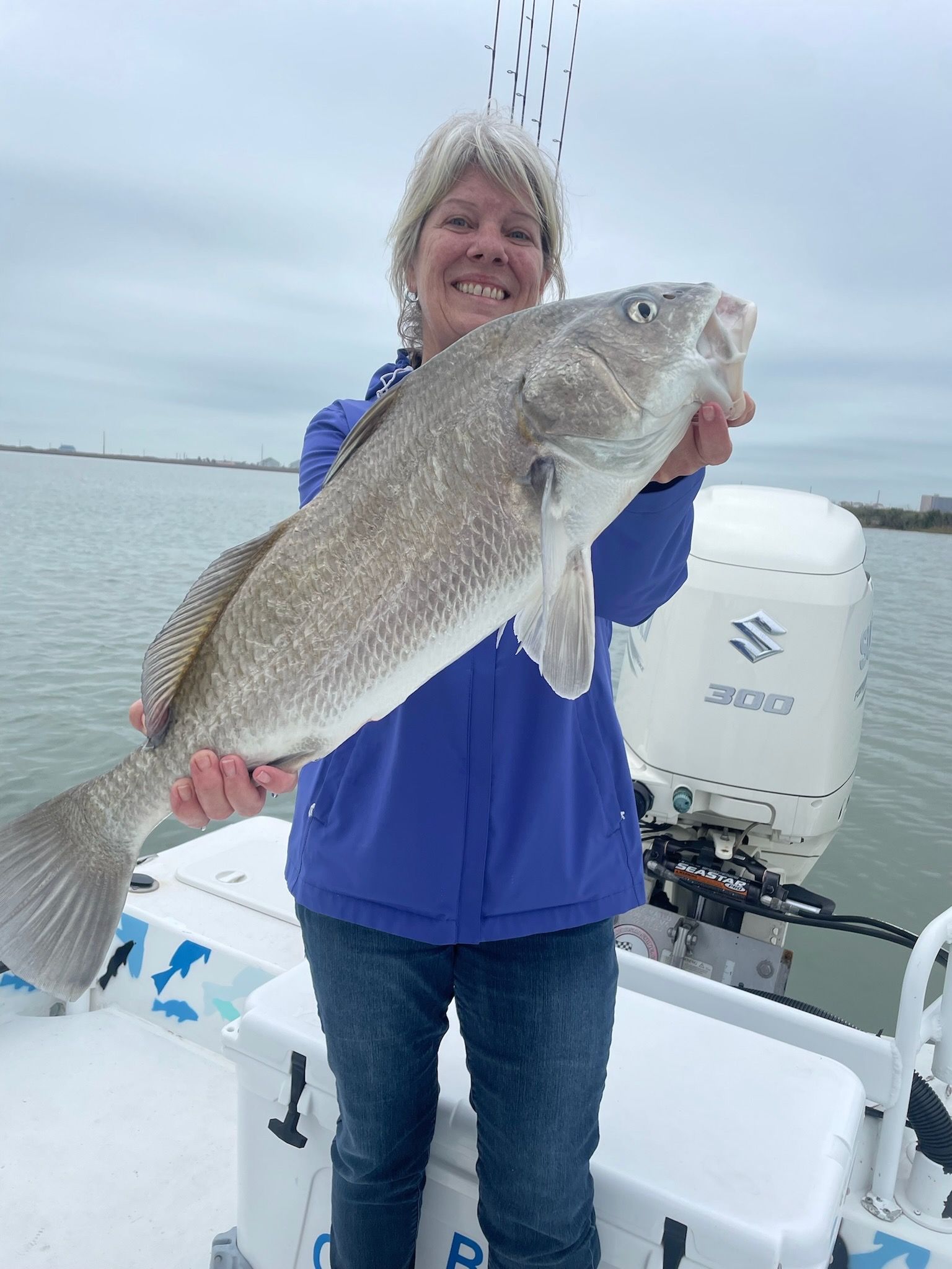 A woman is holding a large fish on a boat.