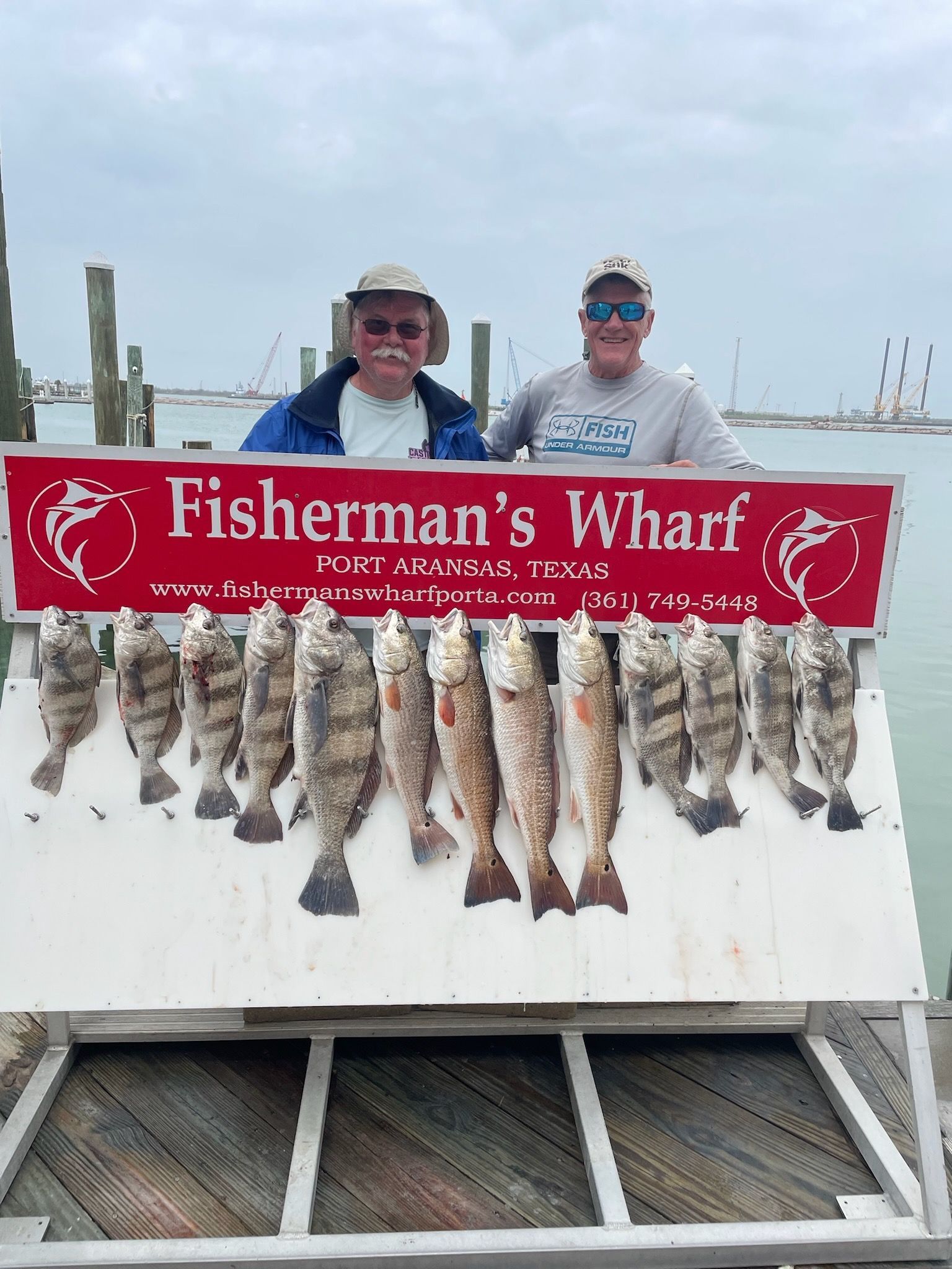Two men standing next to a sign that says fisherman 's wharf