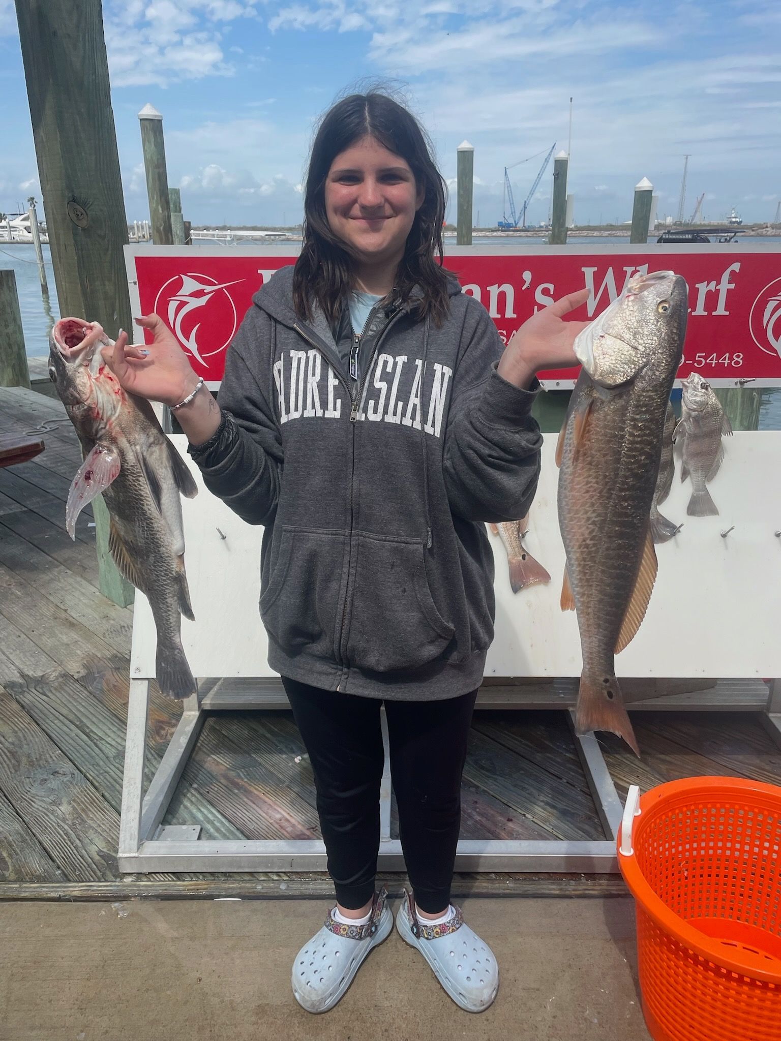 A young girl is holding three fish in her hands.