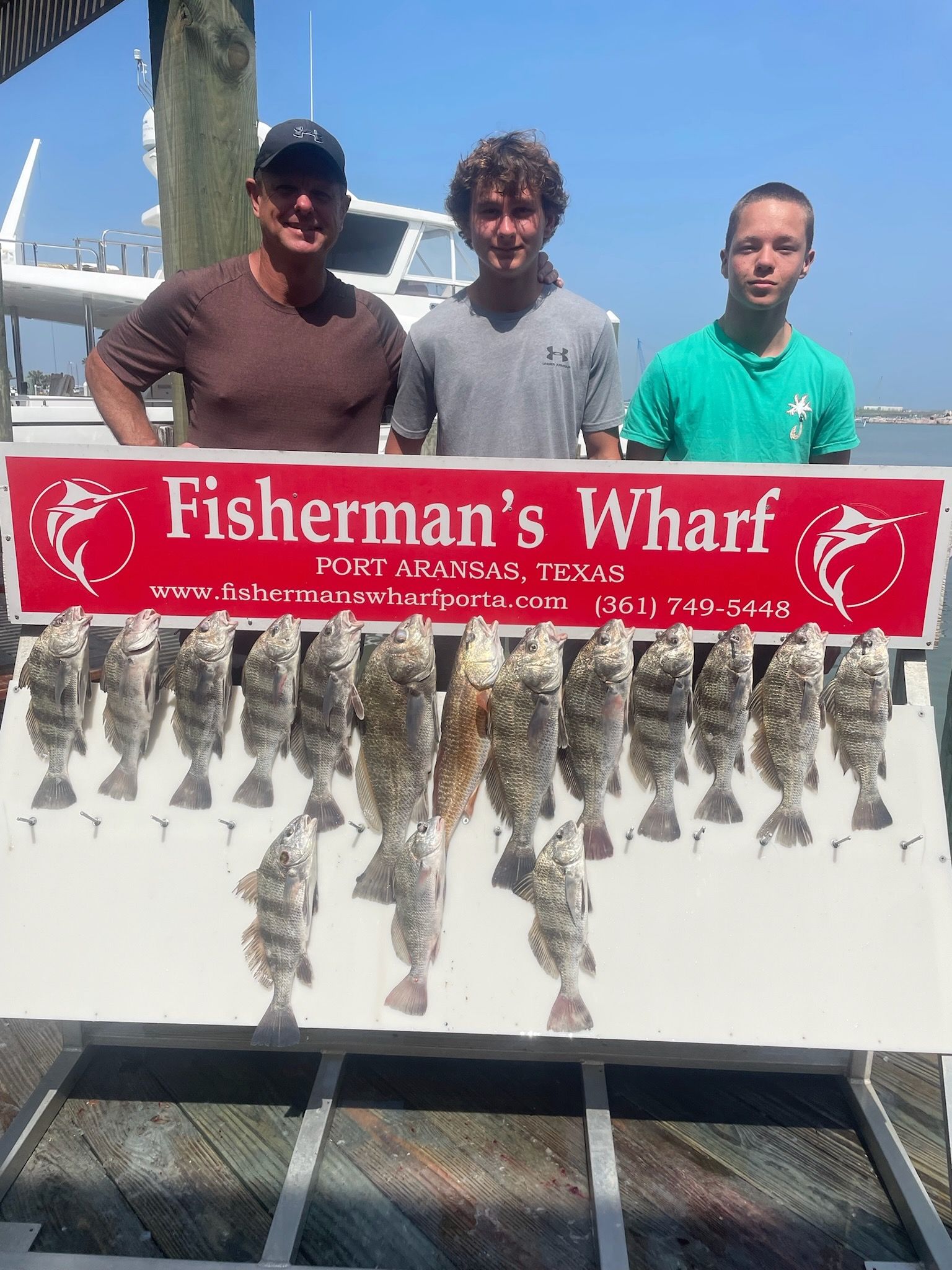 Three men standing next to a sign that says fisherman 's wharf