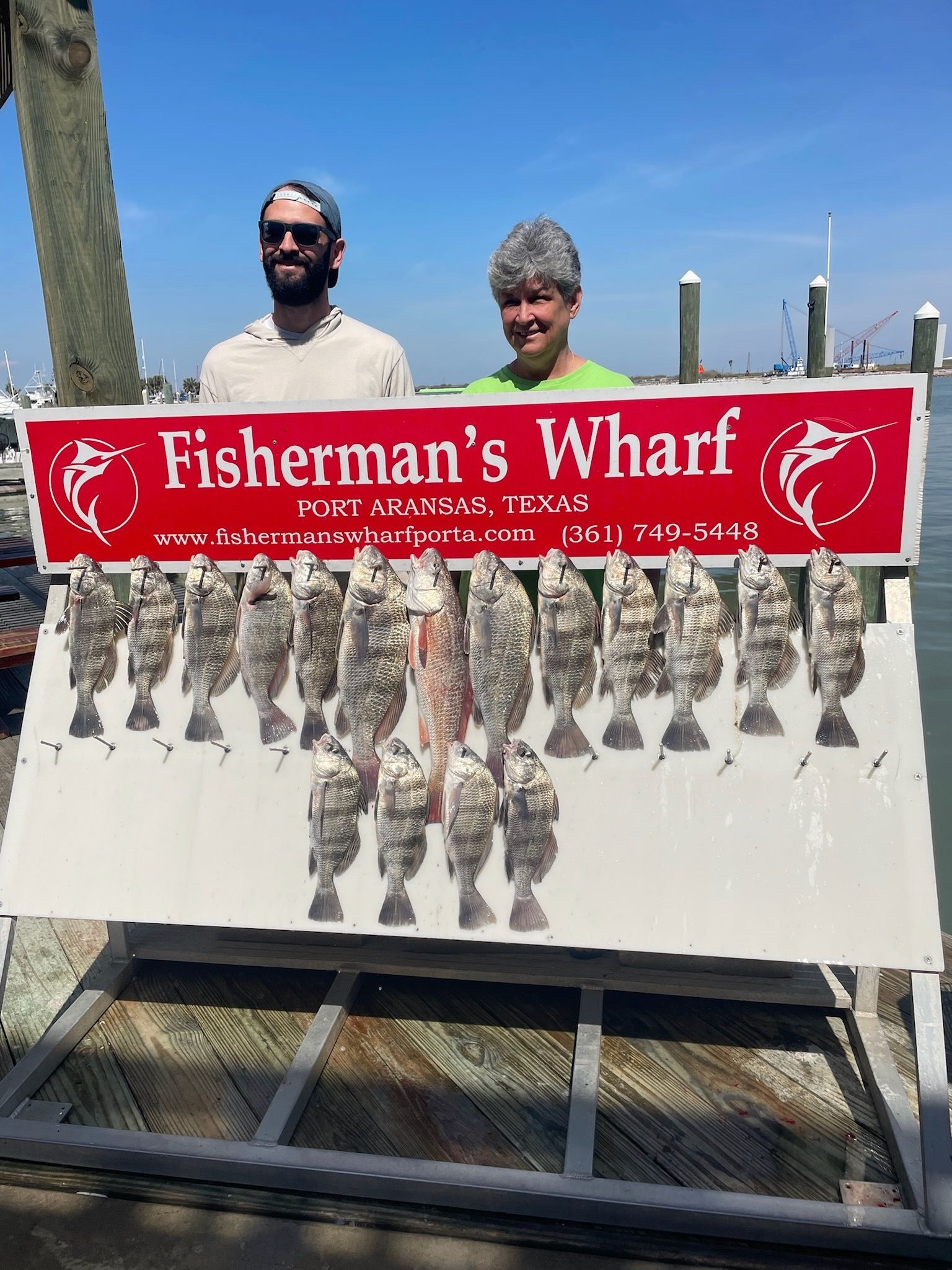 A man and a woman are standing next to a sign that says fisherman 's wharf.