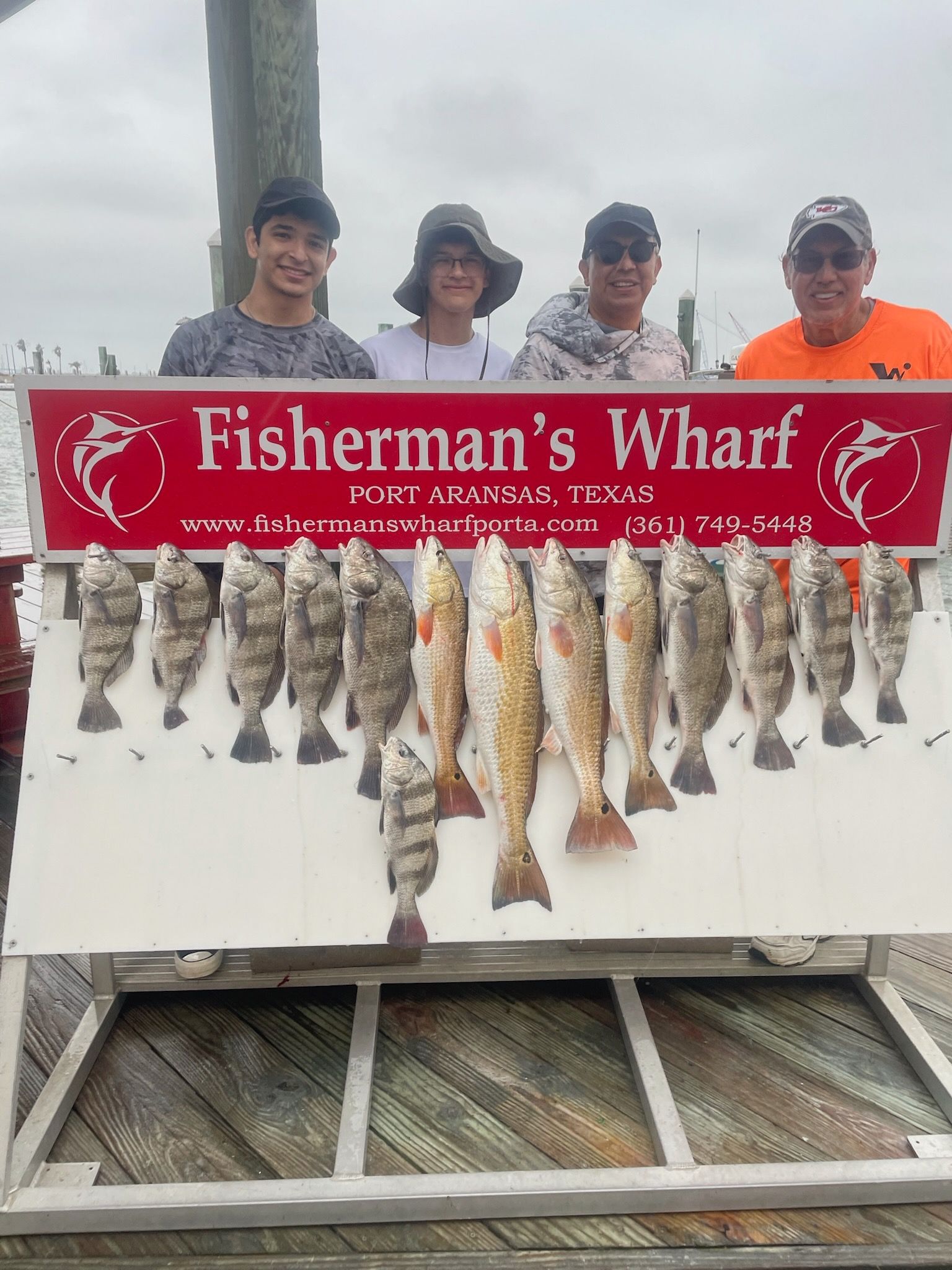 A group of people are standing next to a sign that says fisherman 's wharf.