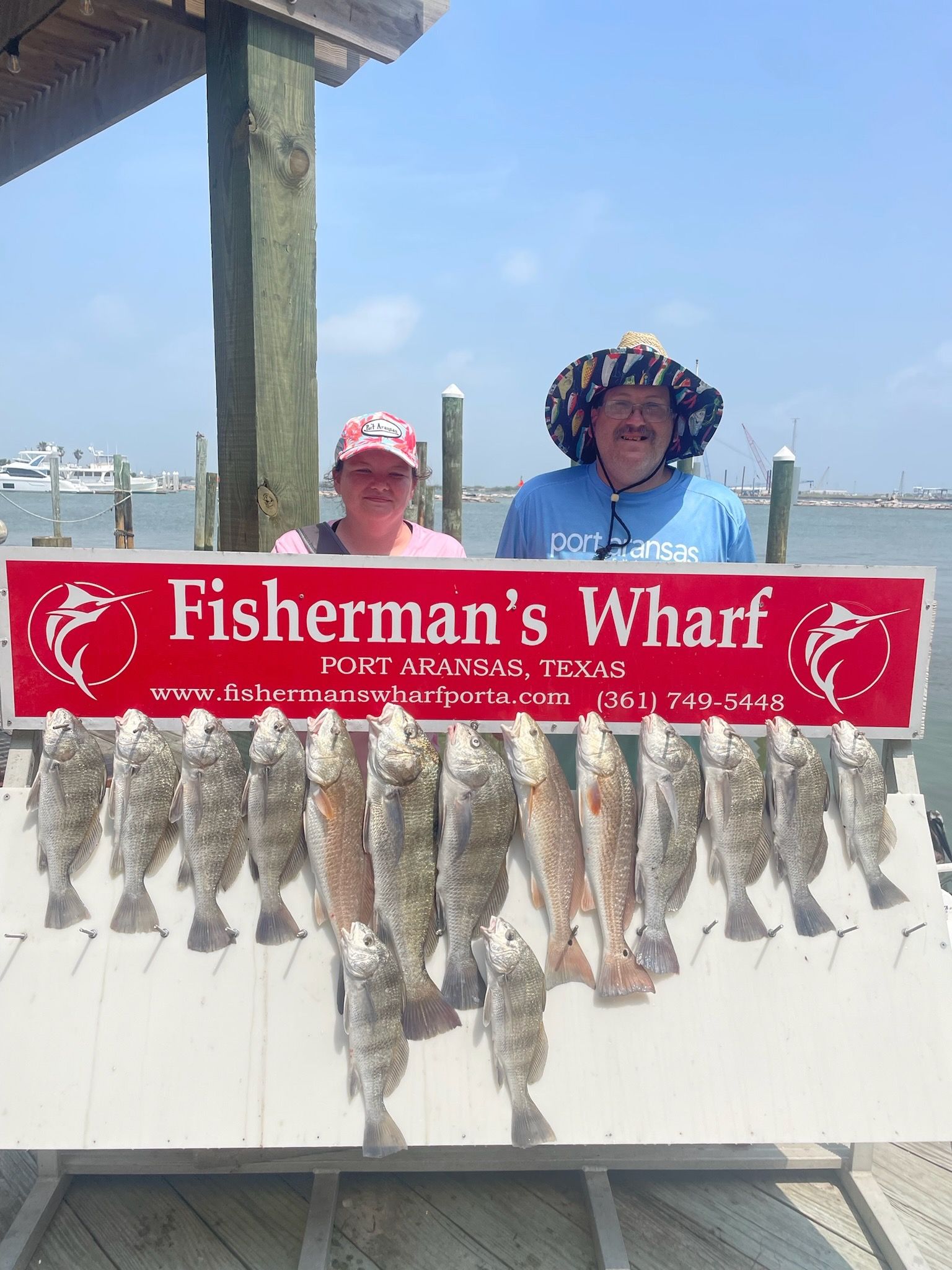 A man and woman holding a sign that says fisherman 's wharf