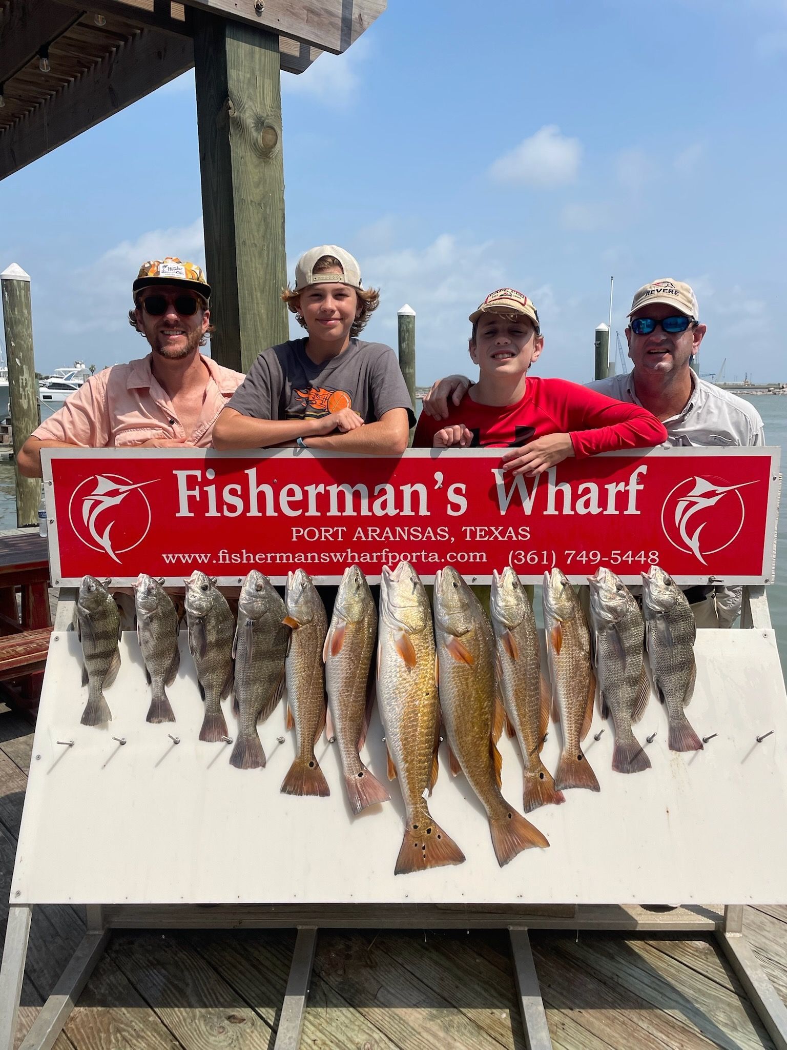 A group of people standing next to a sign that says fisherman 's wharf.