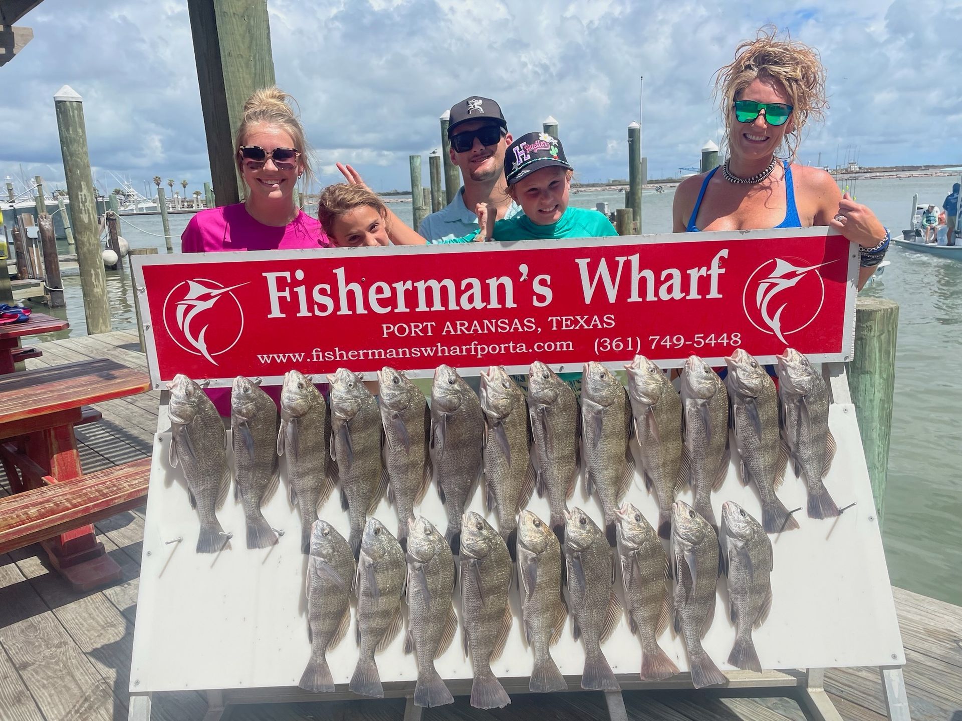 A group of people standing next to a sign that says fisherman 's wharf