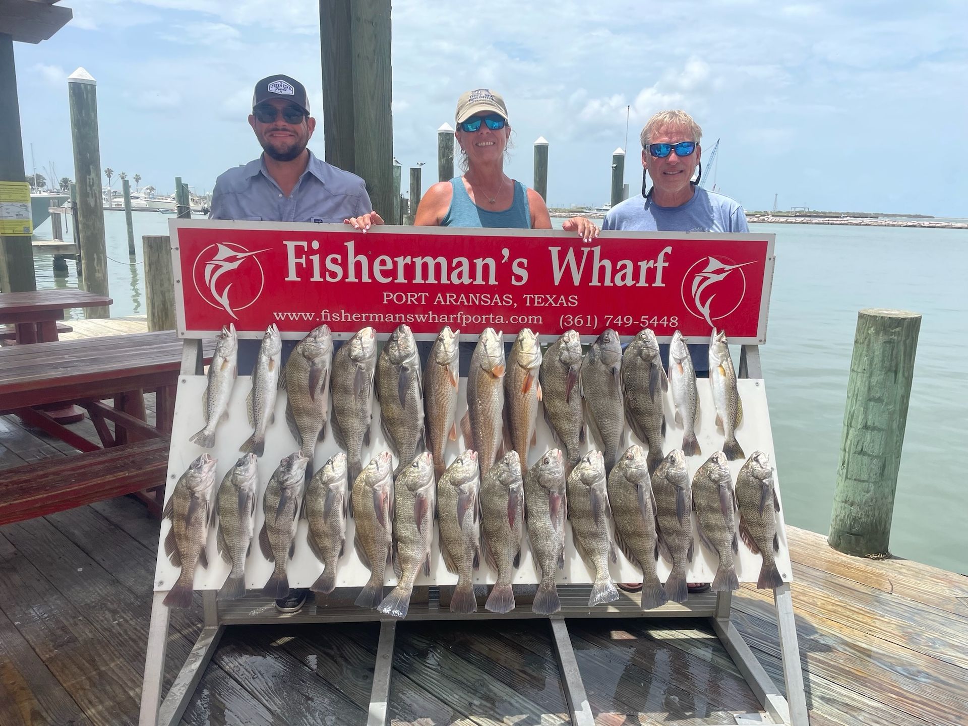 A group of people standing next to a sign that says fisherman 's wharf.
