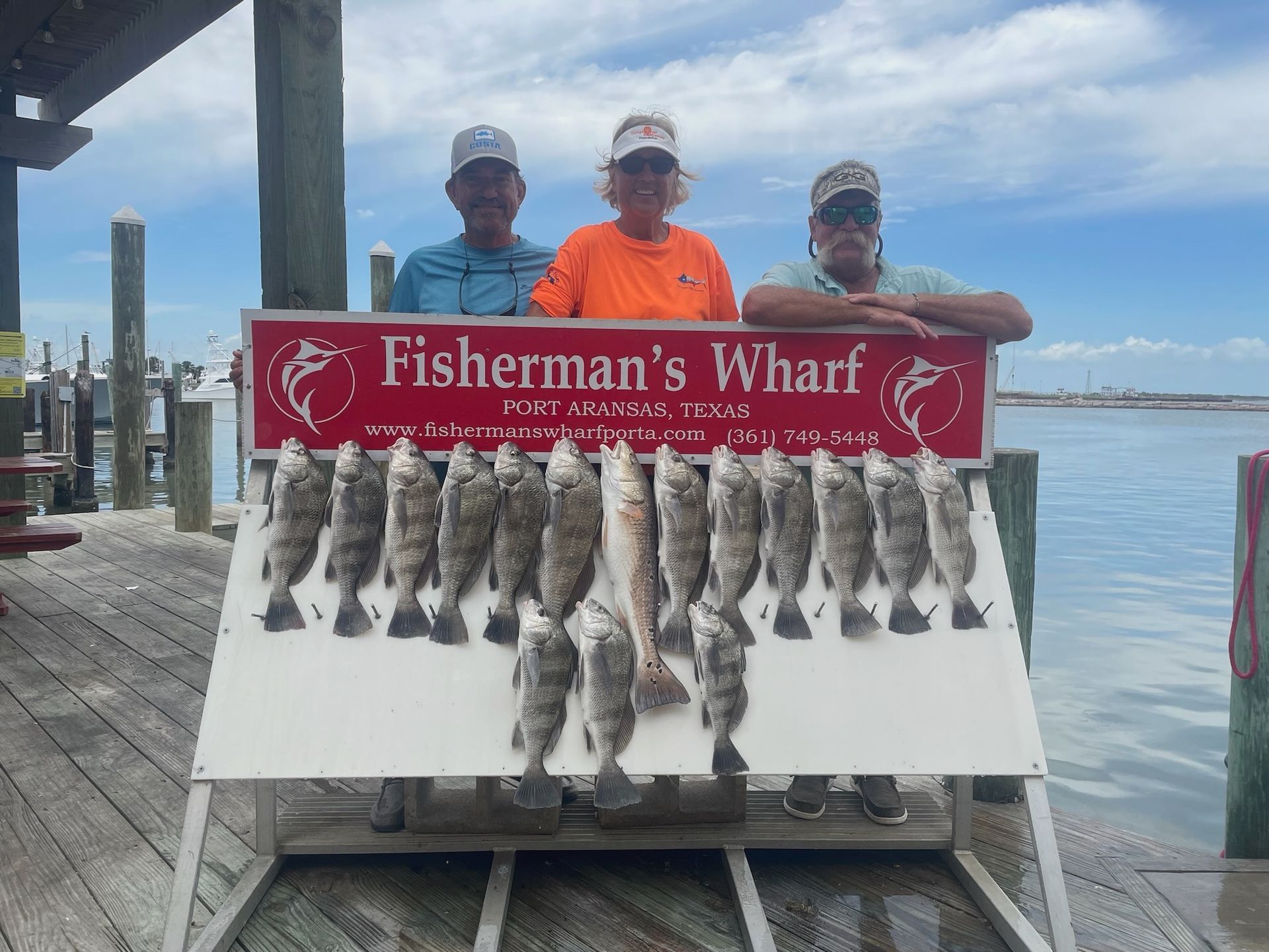 Three men standing next to a sign that says fisherman 's wharf
