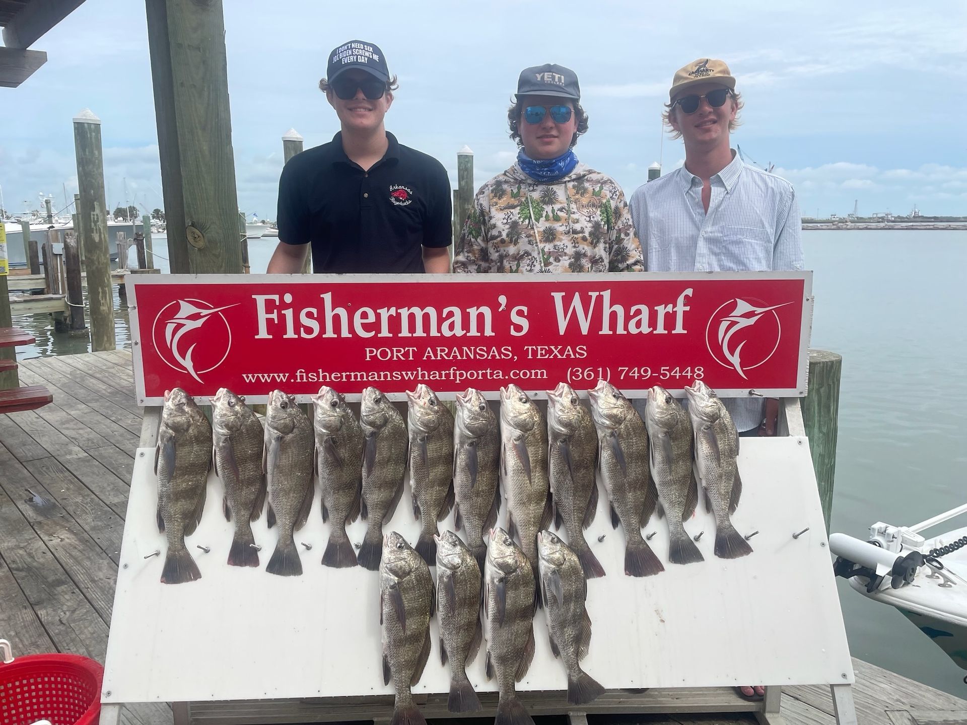 Three men are standing next to a sign that says fisherman 's wharf.