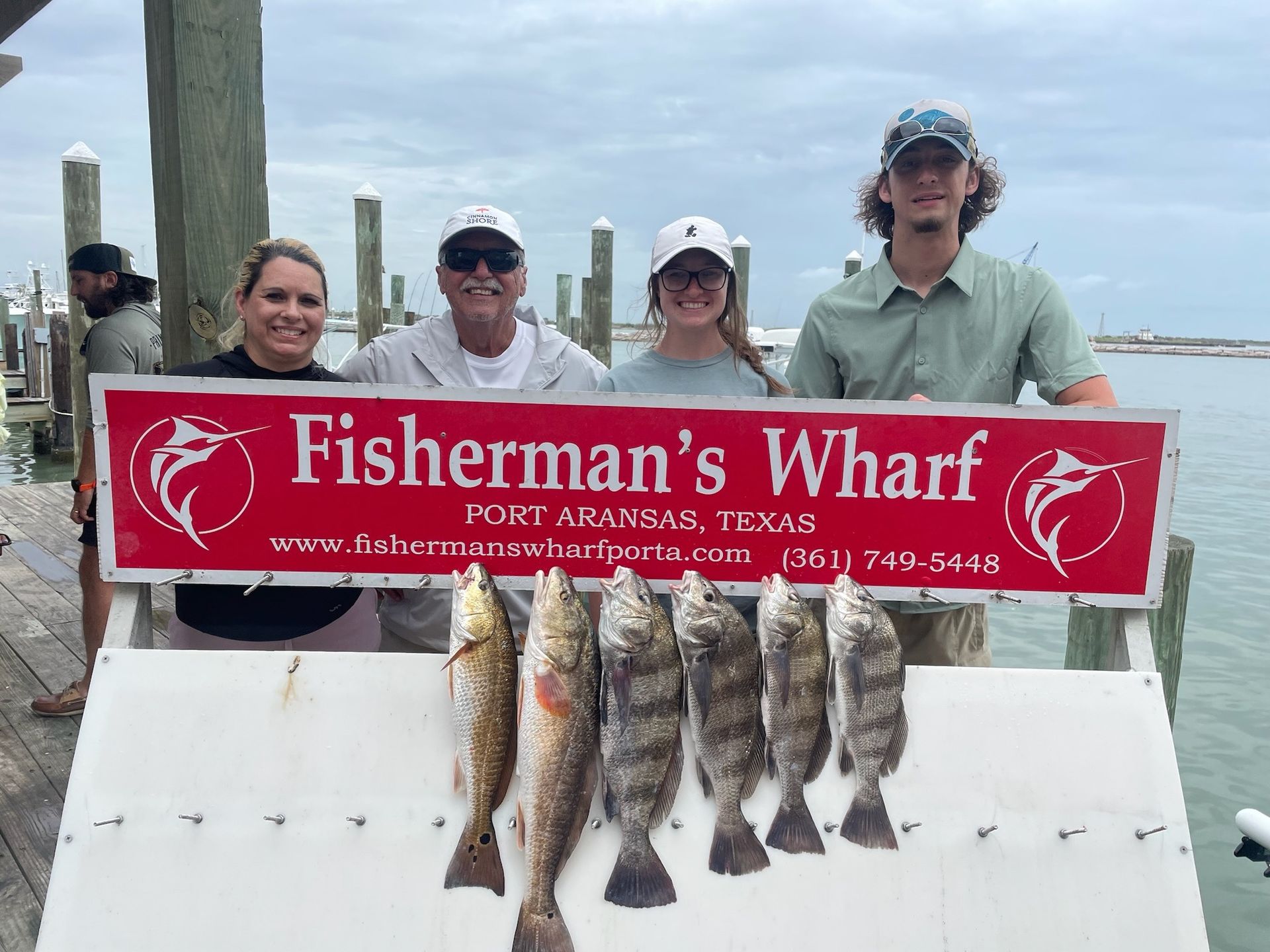 A group of people standing next to a sign that says fisherman 's wharf