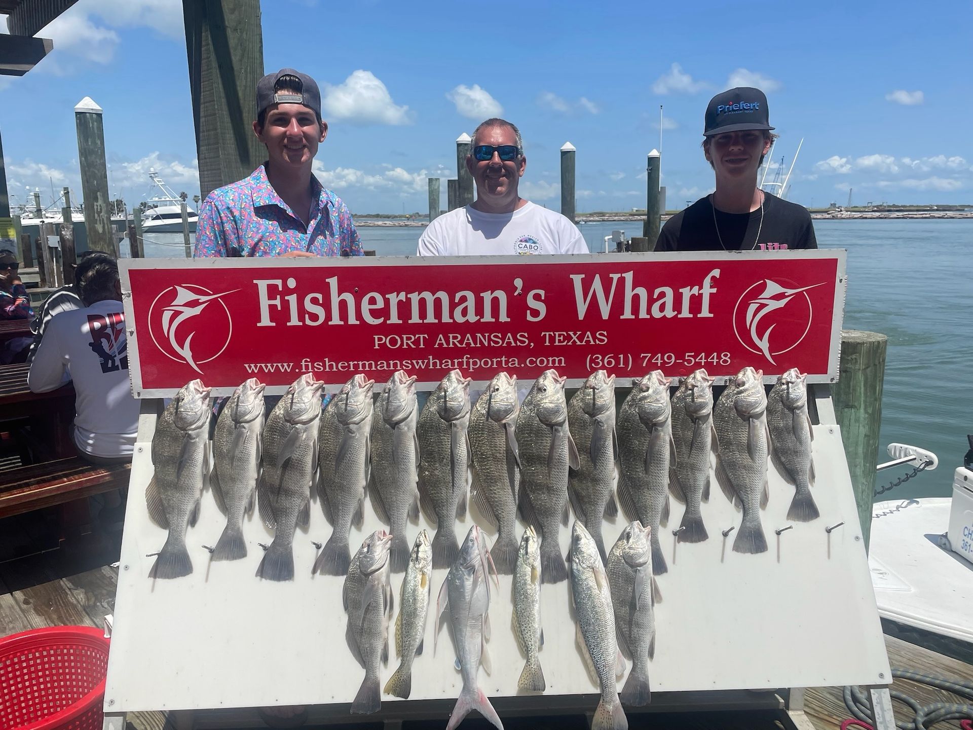 A group of men are standing next to a sign that says fisherman 's wharf.