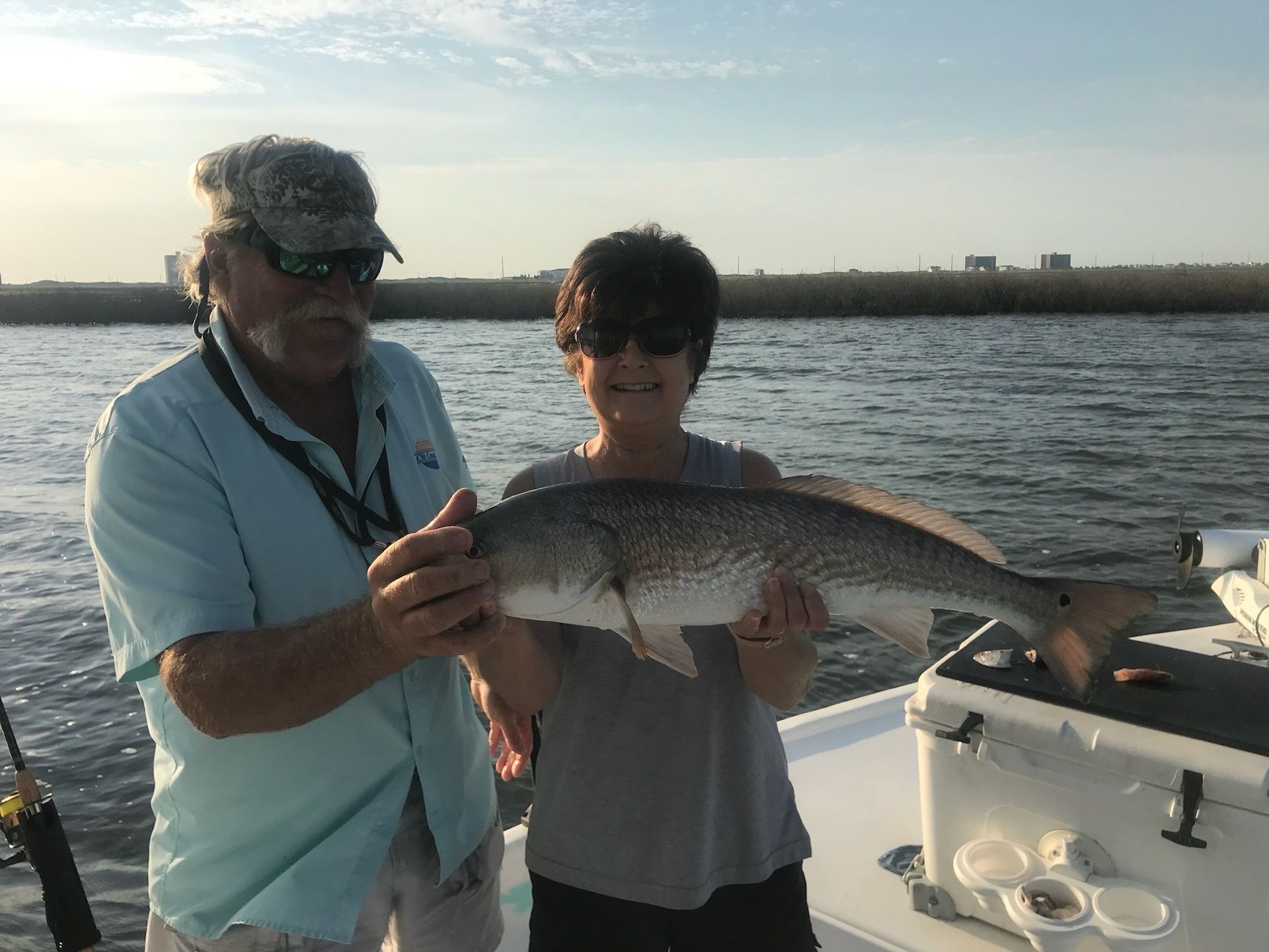 A man and a woman are holding a large fish on a boat.