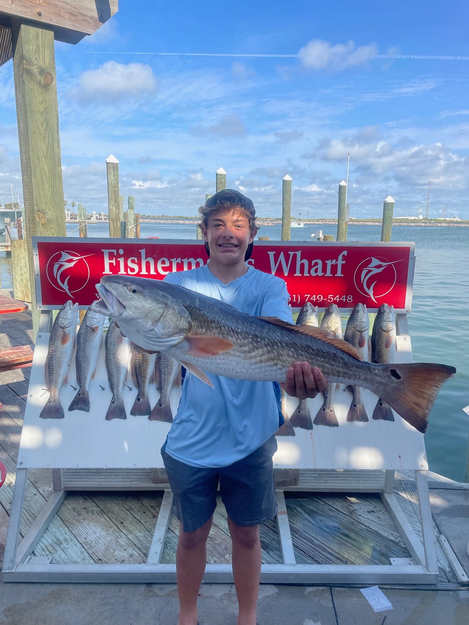 A man is holding a large fish in front of a display of fish.